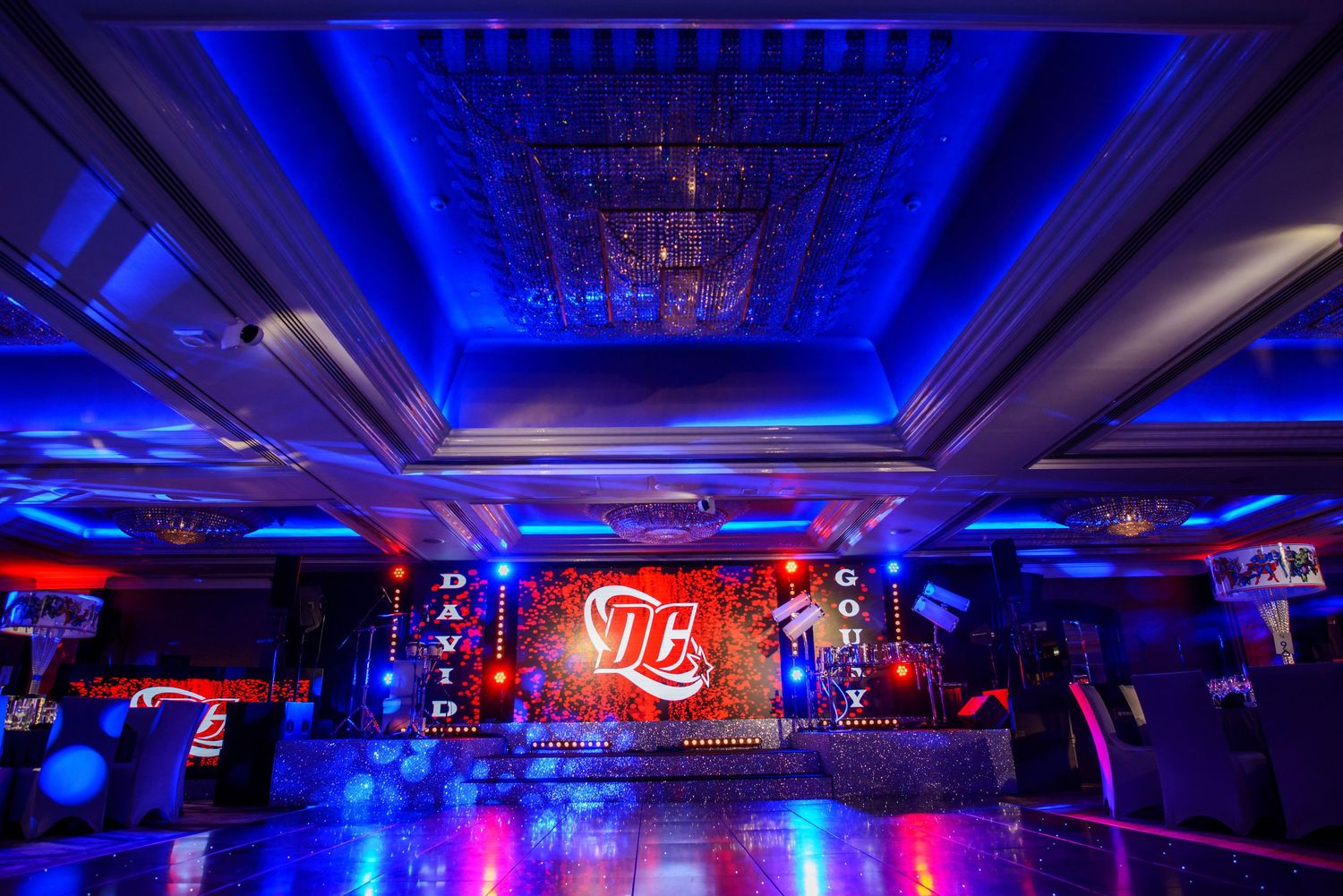 Nightclub interior illuminated in vibrant blue lighting with modern decor and multiple chandeliers hanging from the ceiling.