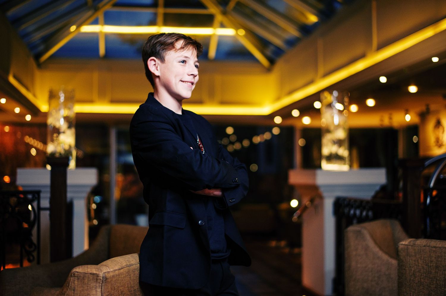 A person sits at a bar counter in a dimly lit restaurant with warm lighting and modern decor.