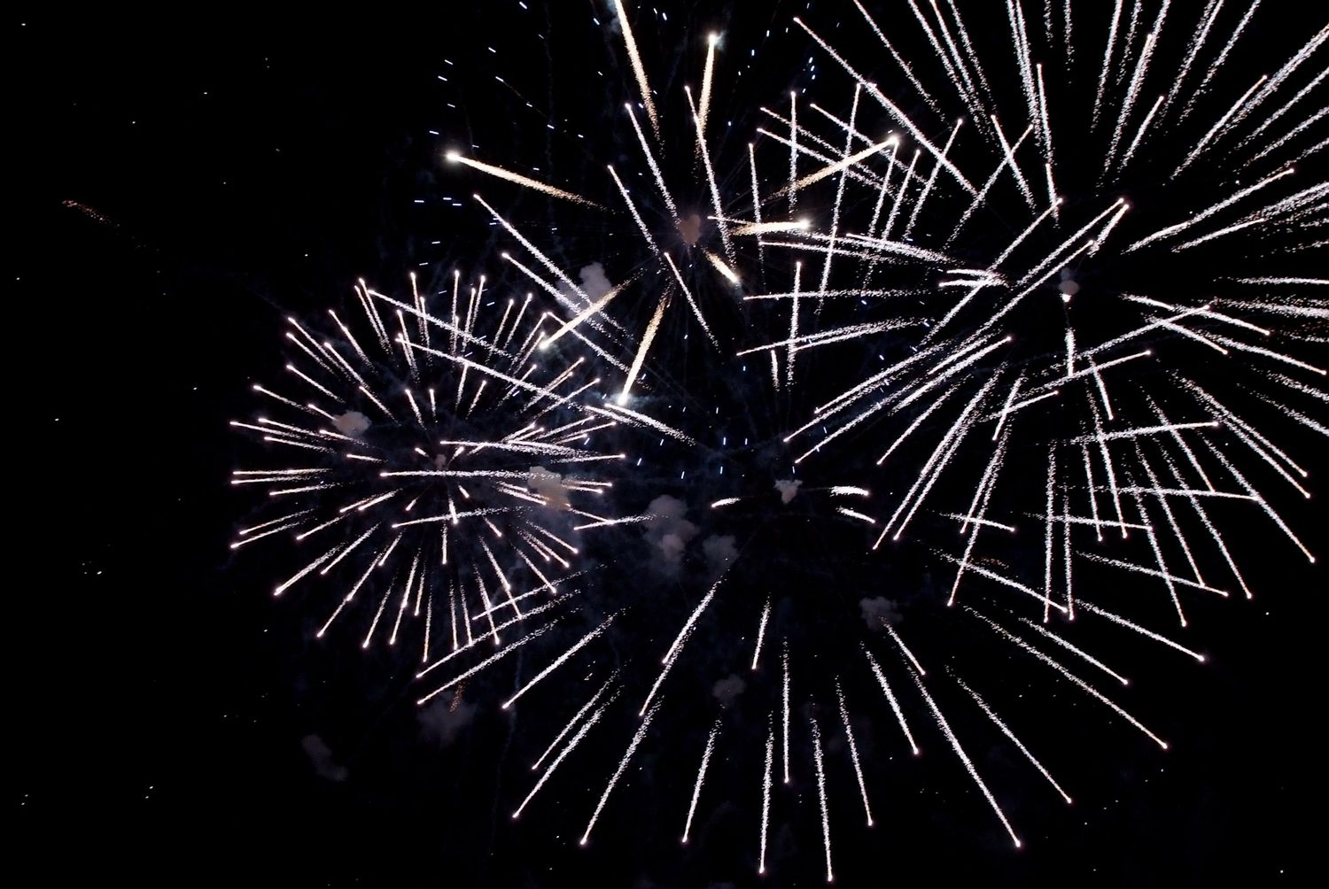 Silver fireworks bursting in night sky creating dramatic starlike patterns.