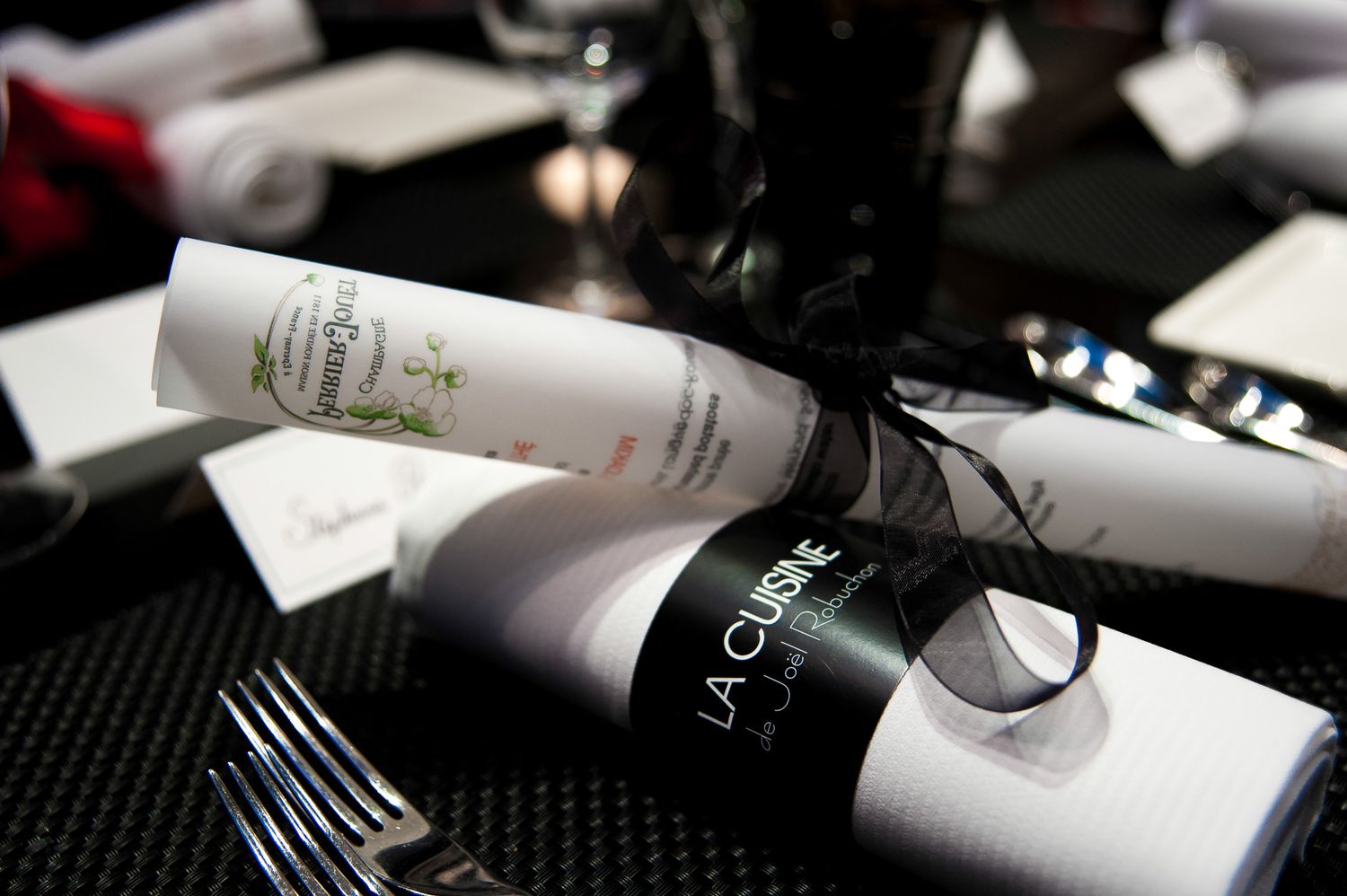 Closeup of wine bottles and table settings in dim lighting.