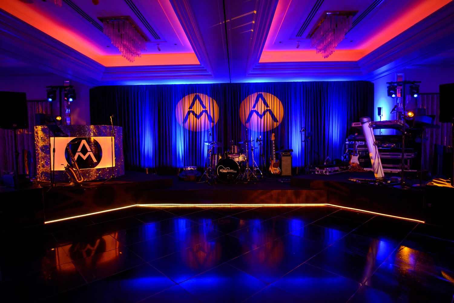 Event venue with dramatic blue and red lighting illuminates modern ballroom setup with sleek decor and staging.