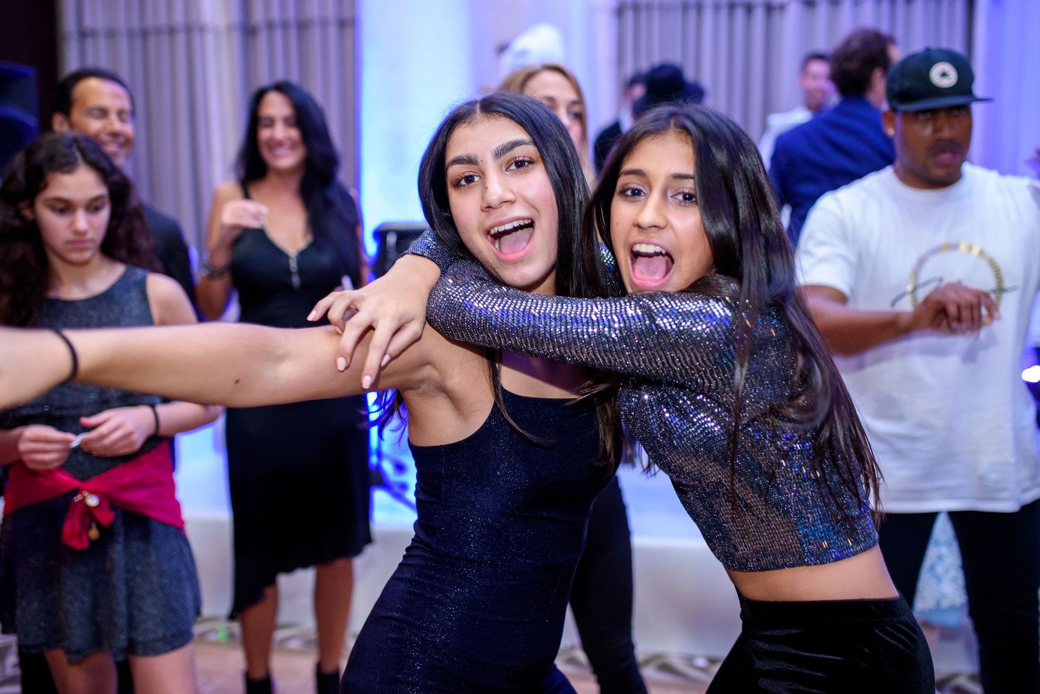 A group of dancers in casual attire practicing choreography moves in a dance studio with mirrored walls.