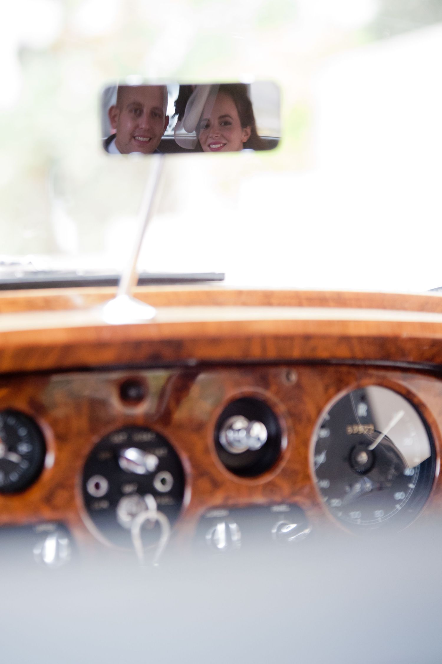 A close-up view of vintage car dashboard gauges with wood trim and chrome accents.