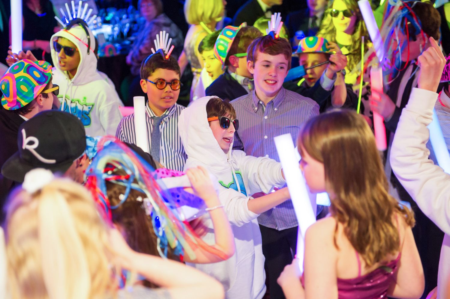 Enthusiastic crowd celebrating at a nightclub with colorful lighting and festive atmosphere.