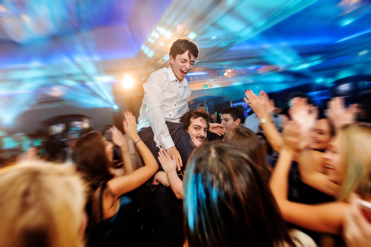 Blurred motion shot of dancing crowd at a nightclub with blue lighting and energetic atmosphere.