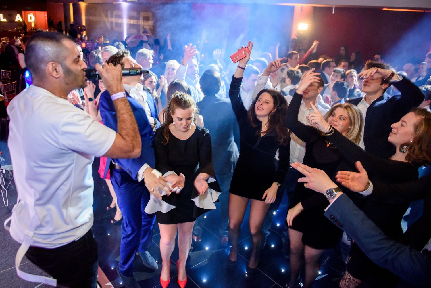 People dancing and socializing at a nightclub with blue lighting and energetic atmosphere.