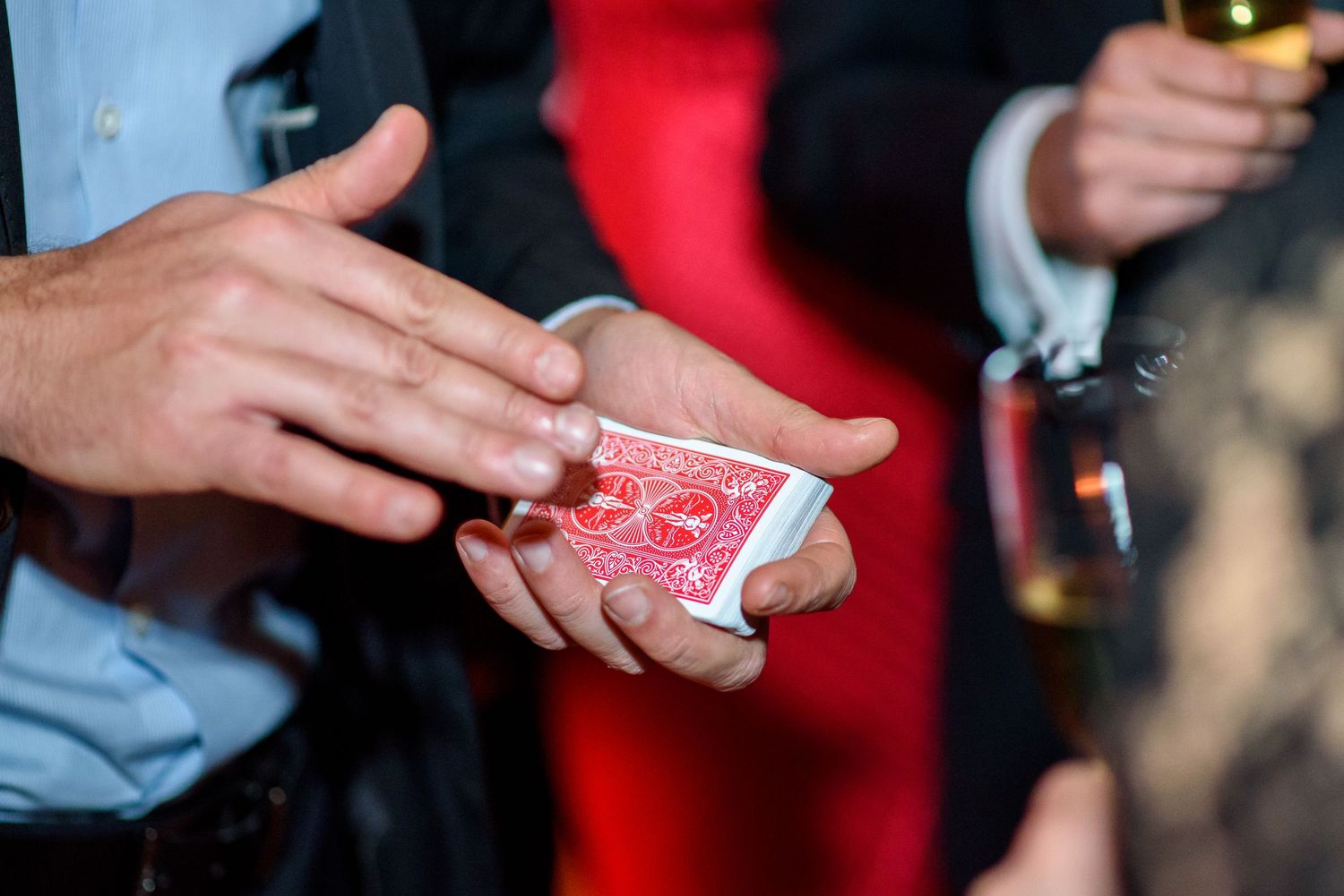 Close-up of hands performing card tricks with red playing cards.