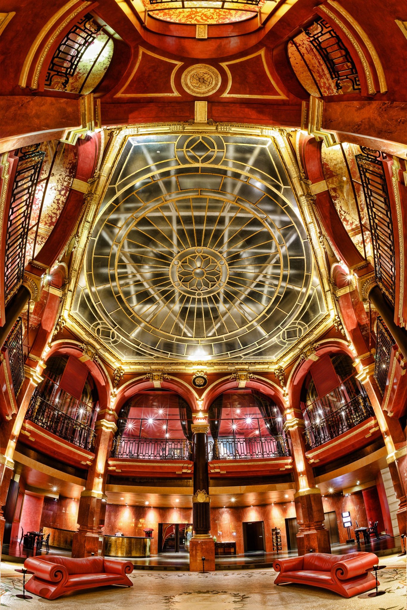 Ornate domed ceiling with art deco details and dramatic lighting in historic venue.
