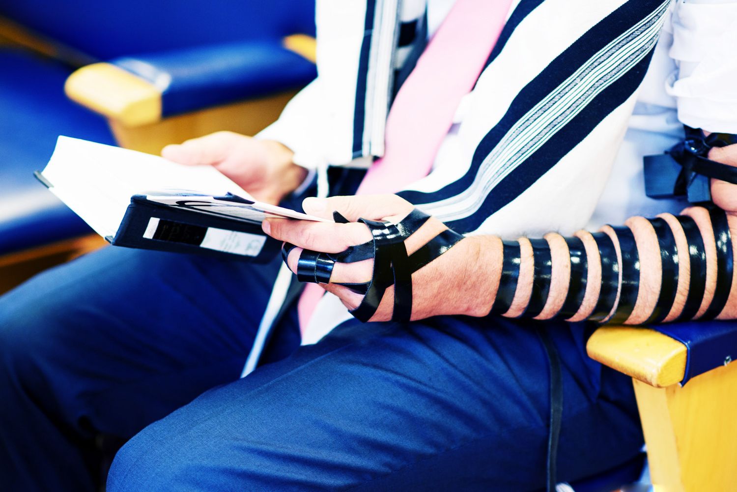 Prayer shawl with black stripes draped over shoulders during Jewish service.