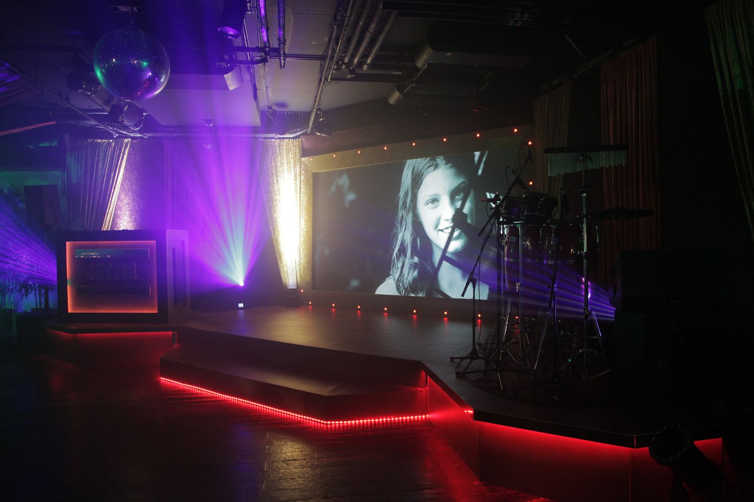 Nightclub interior with purple and red lighting illuminating dark spaces and dance floors.