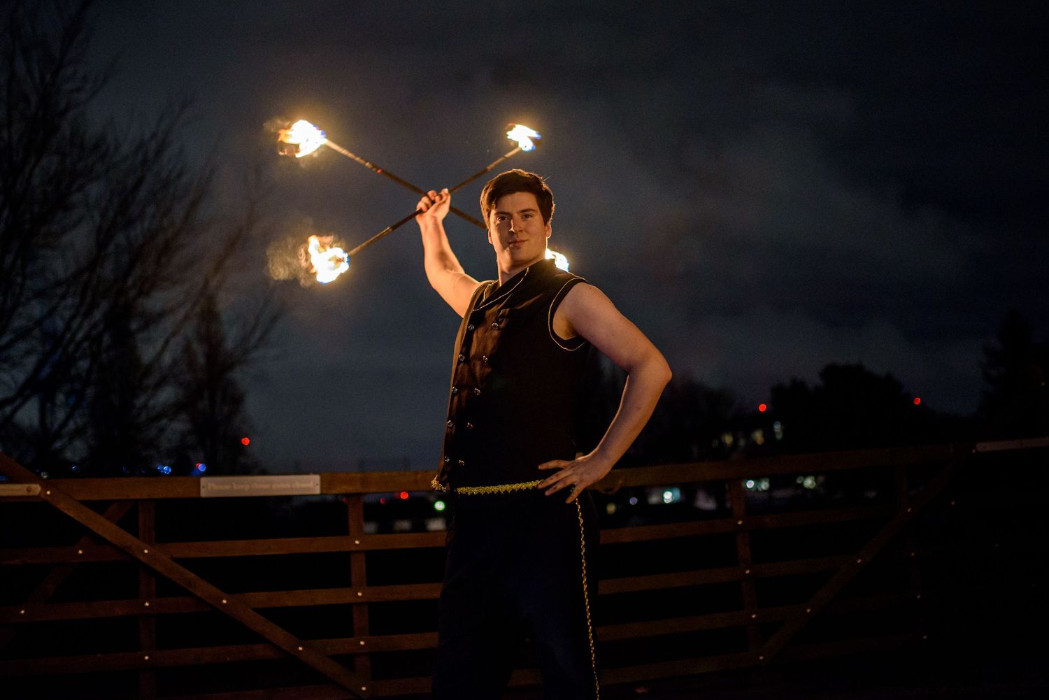 Fire performer spinning flaming torches at night creating dramatic light trails.