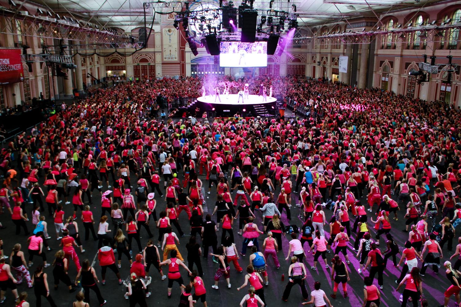 Large crowd gathered at an outdoor concert venue with purple stage lighting.