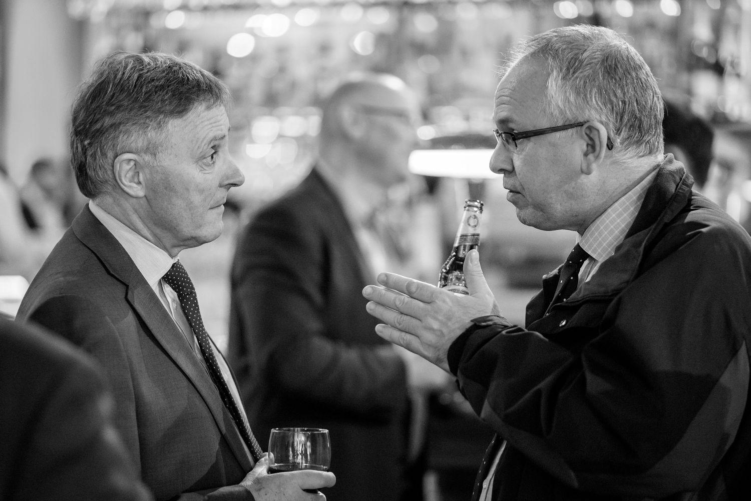 Black and white photo of business professionals networking at formal event.
