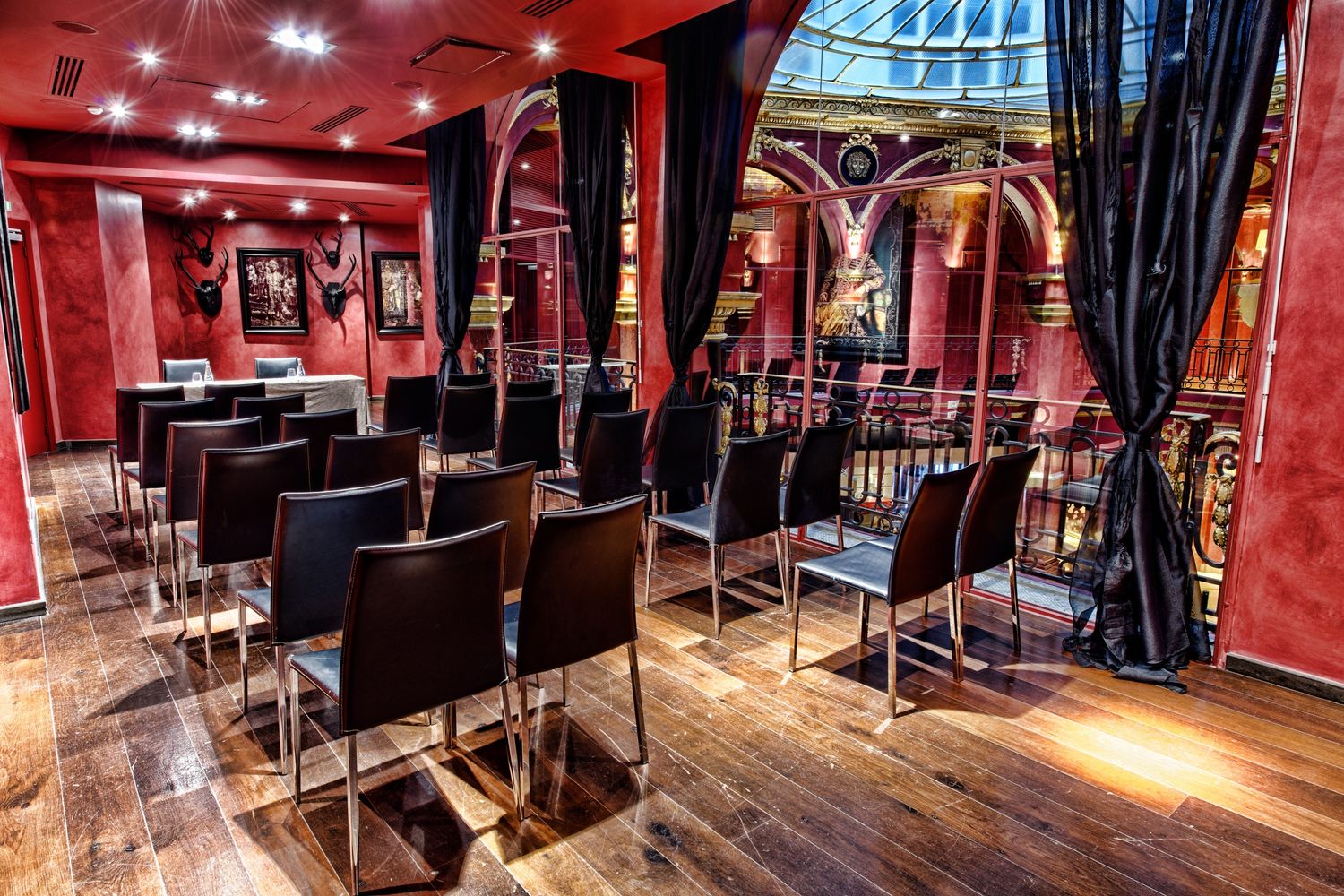Luxurious theater interior with red walls and dramatic lighting showcases plush seating and ornate architectural details.