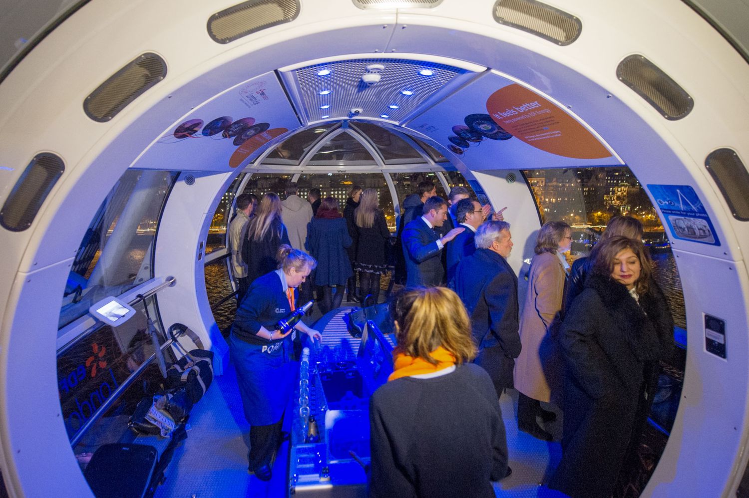 Curved architectural interior with blue lighting and guests at networking event.