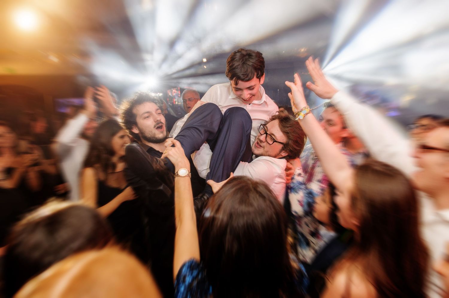 A crowd of people dancing and moving energetically at a nightclub or party with blurred motion effects.