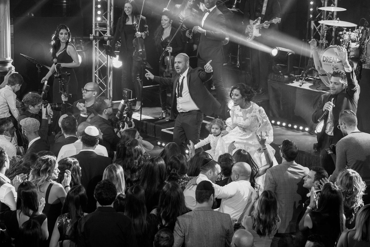 A crowded nightclub scene with people dancing and socializing under colorful lighting.