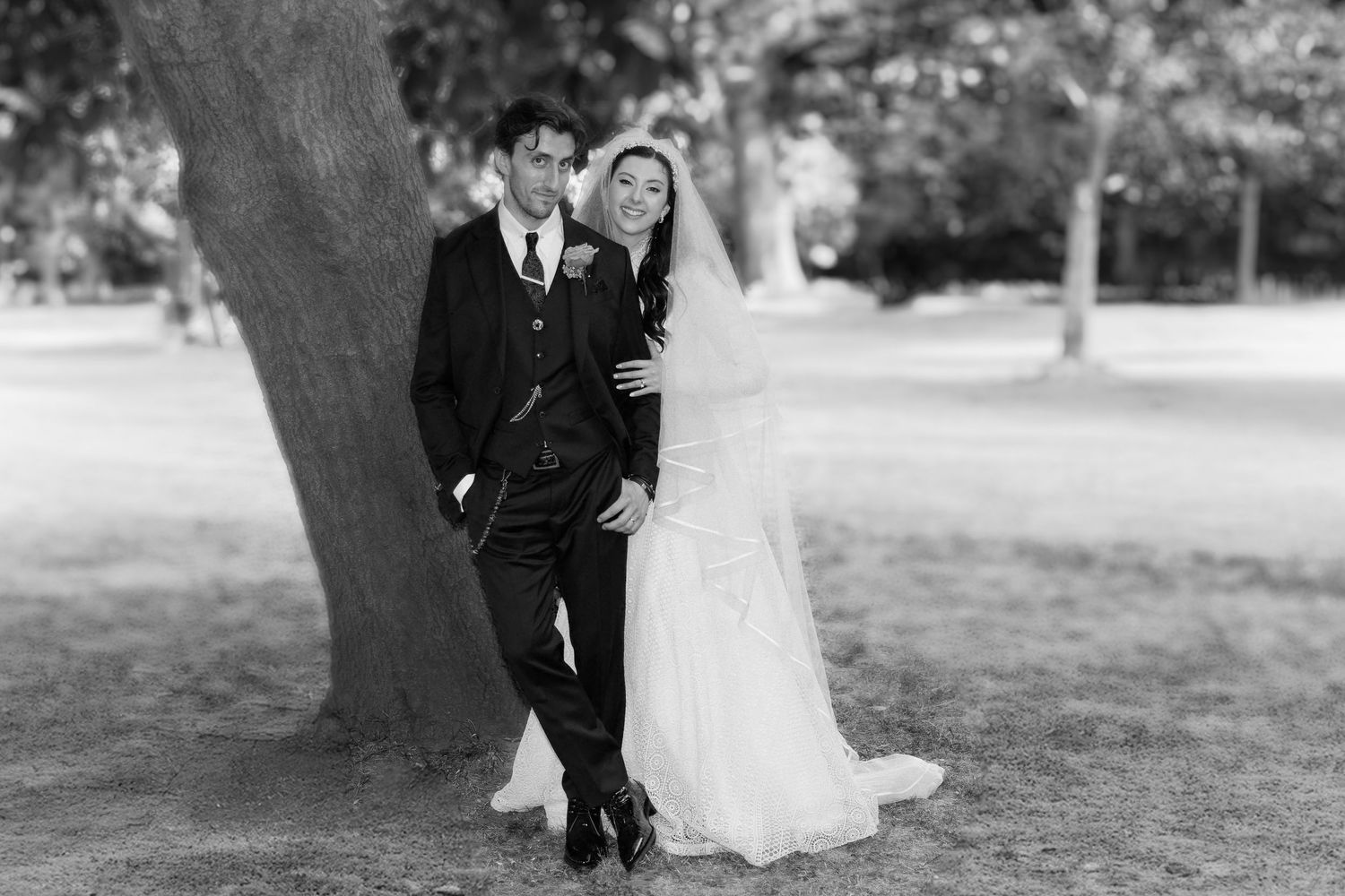 Black and white wedding photos show a couple posing outdoors in formal attire near trees and a garden setting.
