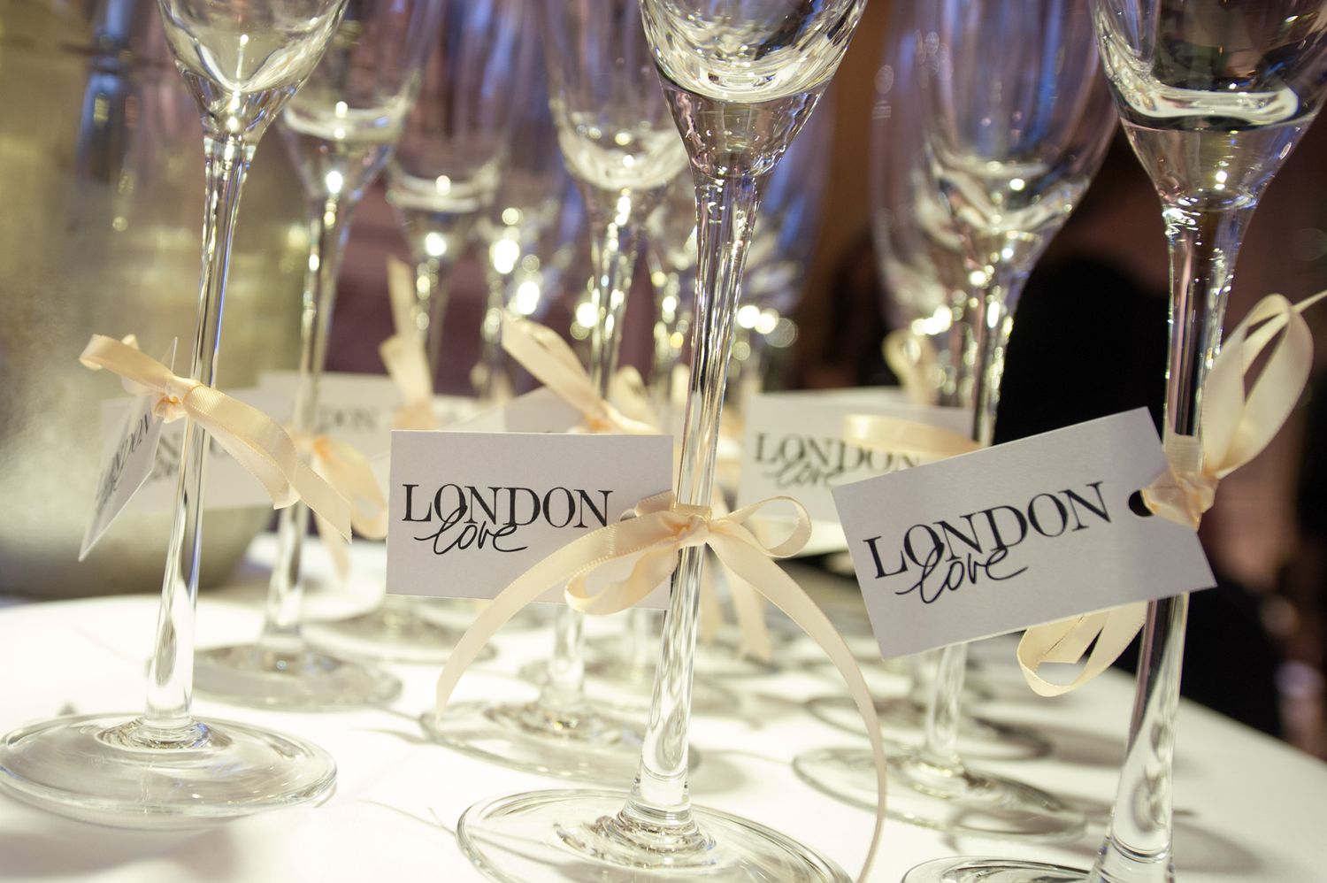 Crystal champagne glasses with London-branded name tags at an upscale event.