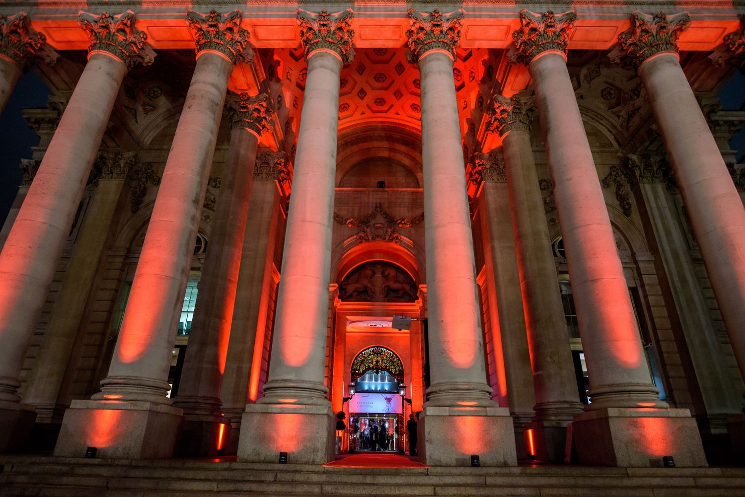 Dramatic exterior columns illuminated in red lighting at night.