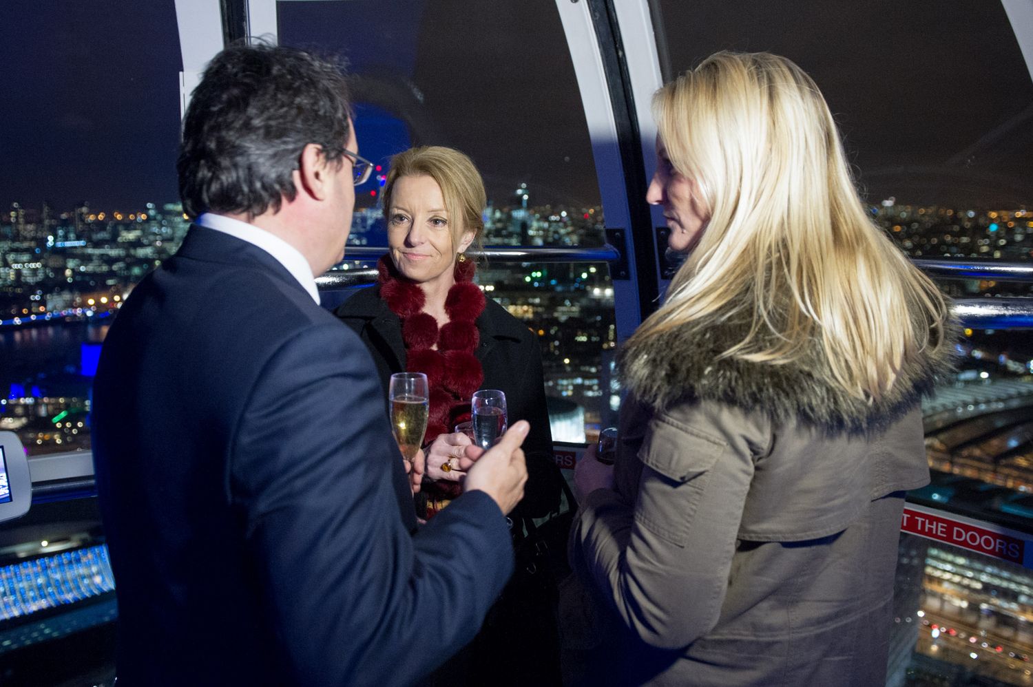 Group of people viewing city lights from a dark observation area with digital displays.