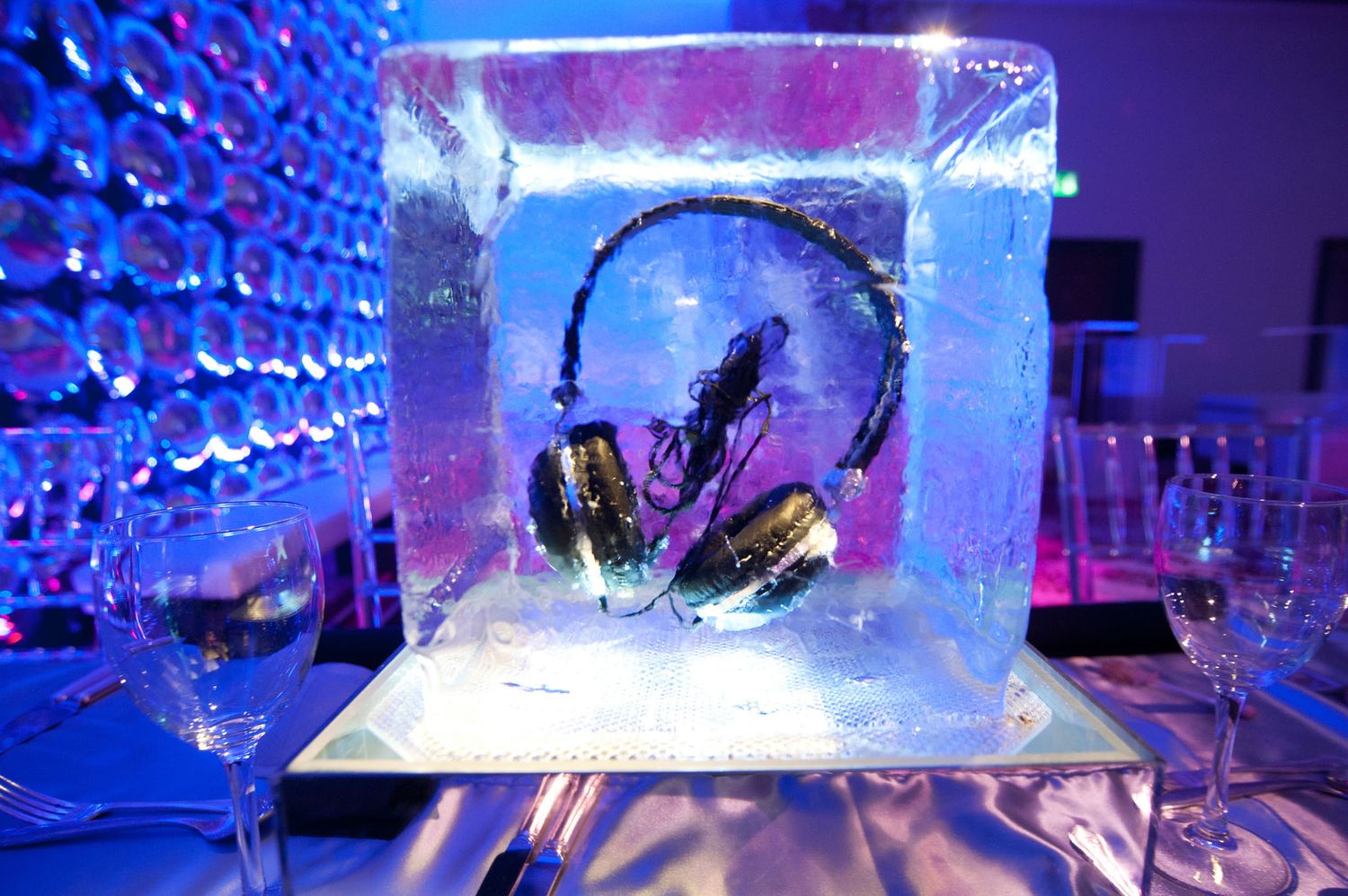 Ice sculptures of musical instruments glow with blue and purple lighting at an elegant event display.