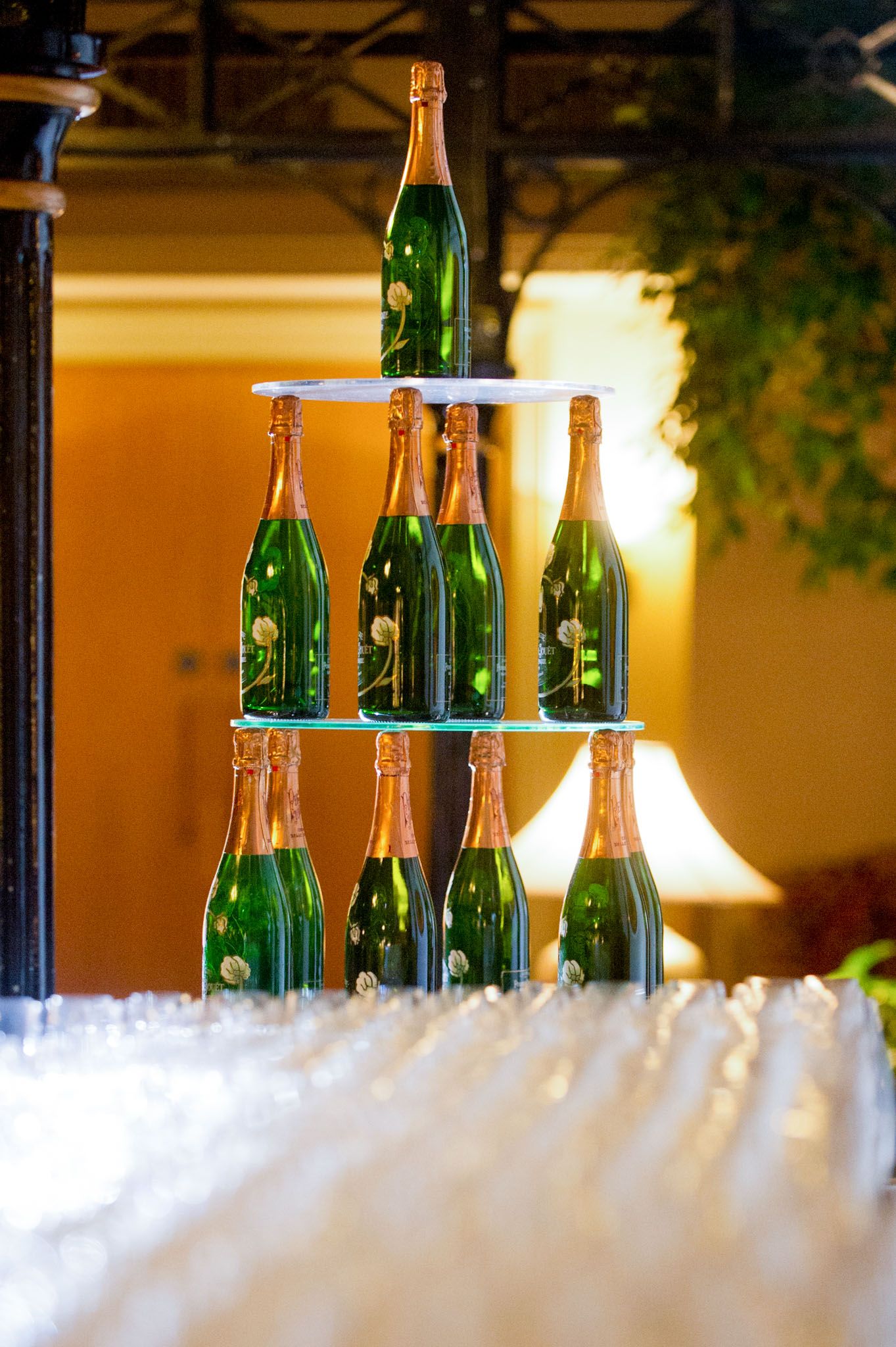 Green glass bottles arranged in pyramid formation on white tablecloth.