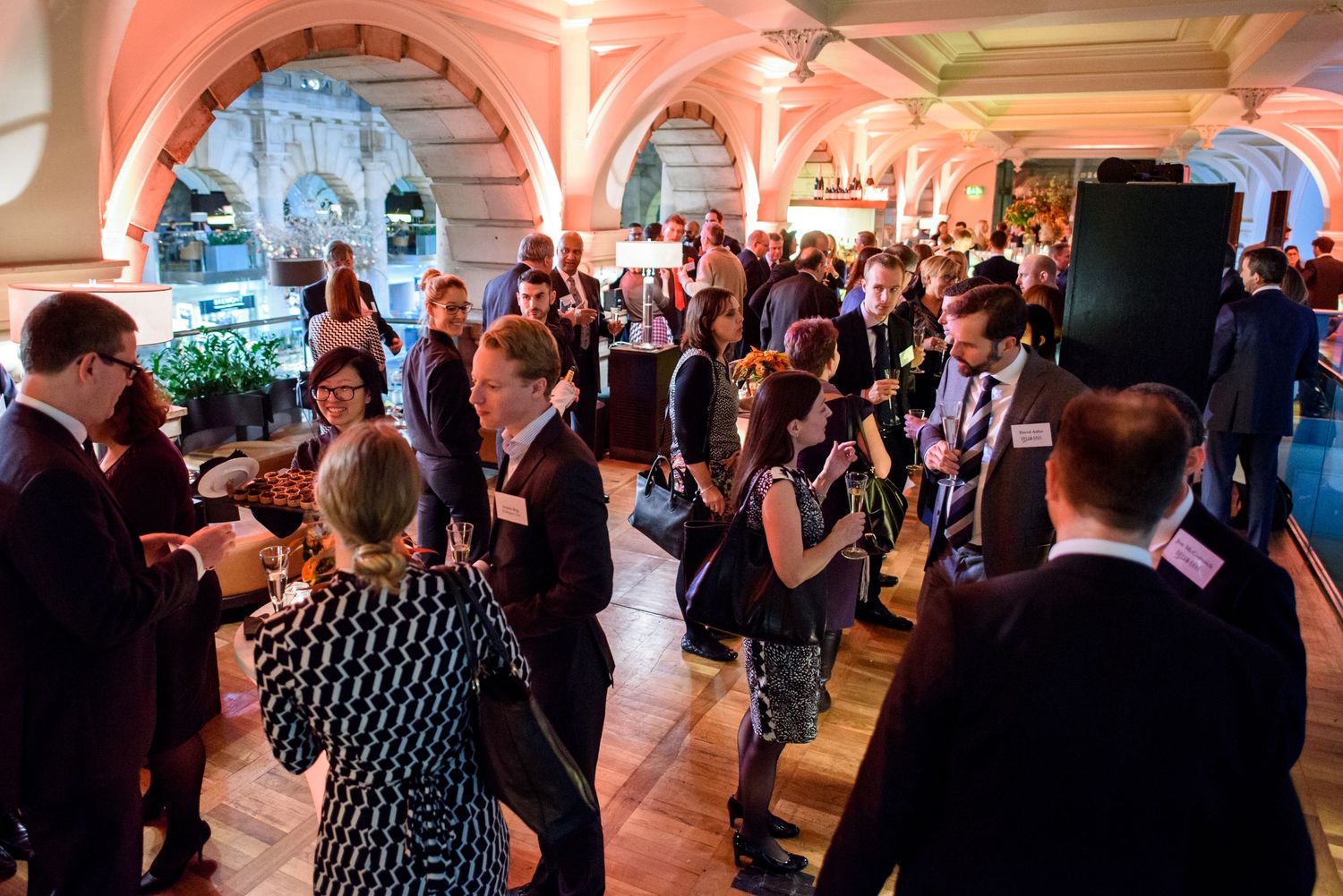 Large banquet hall filled with wedding guests under elegant arched ceilings and warm lighting.