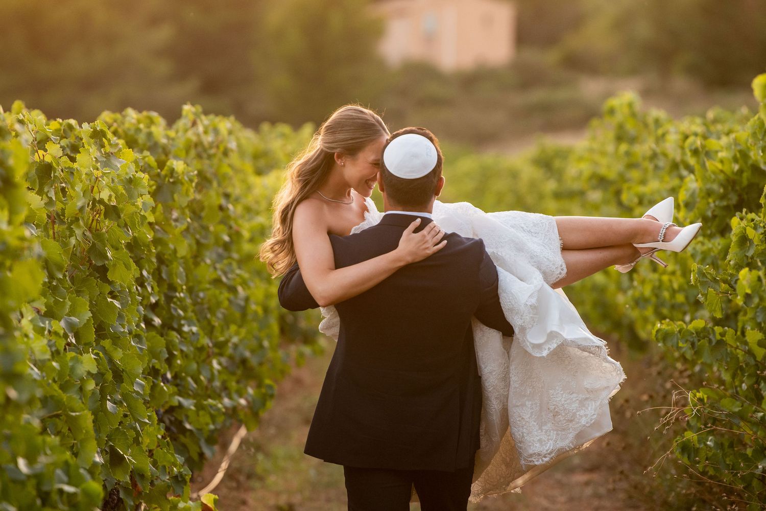 A romantic sunset photoshoot in a lush vineyard with warm golden lighting.