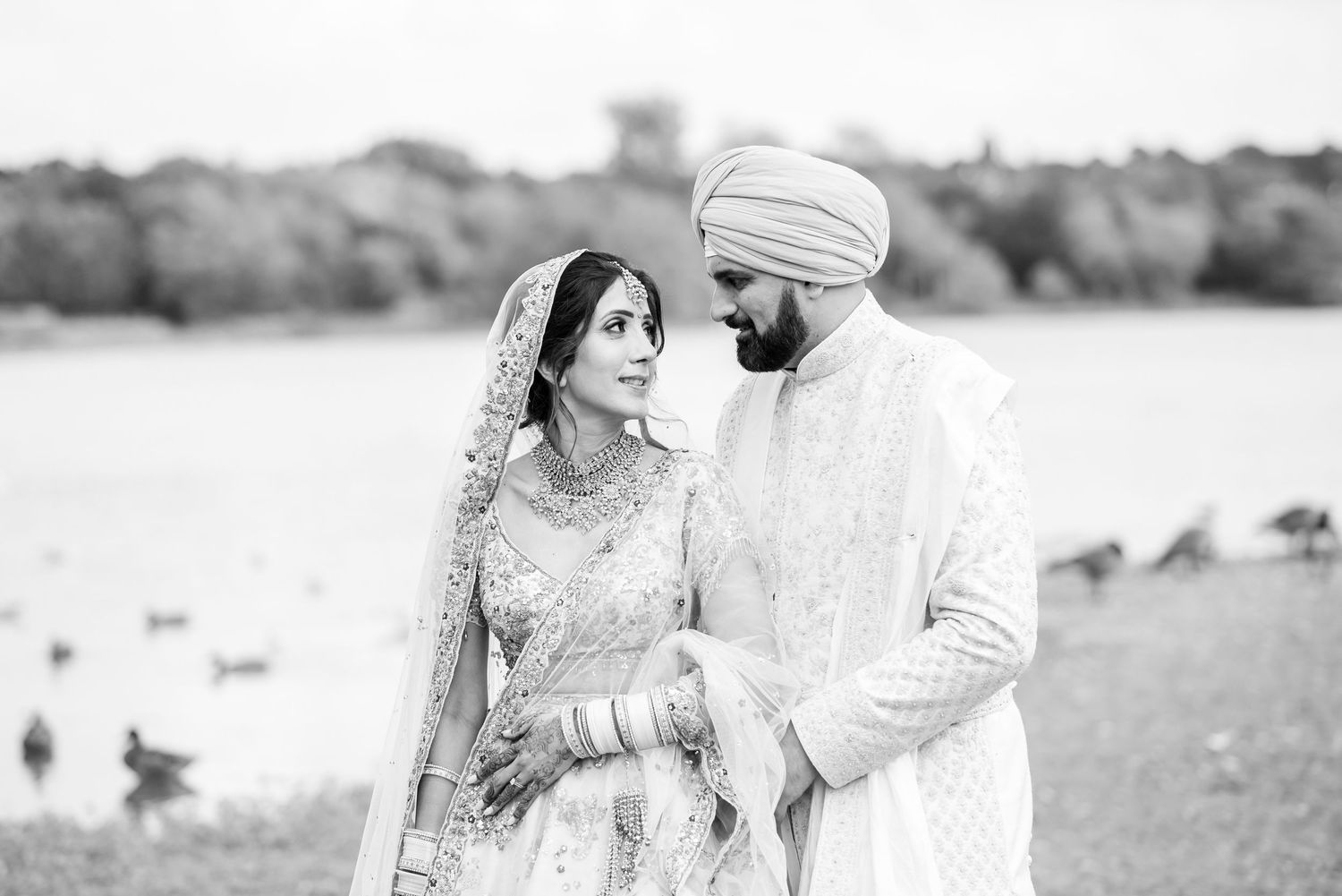 A couple shares romantic moments in a field during their engagement photo session in black and white.