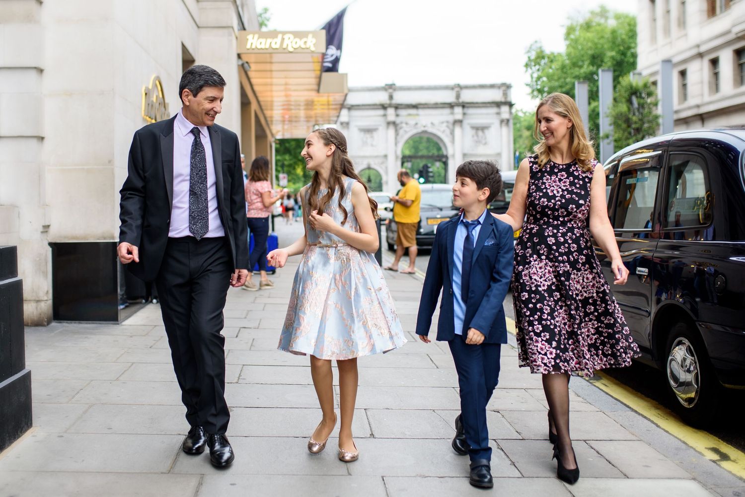 Group of people walking together on a city street in formal attire during a special occasion.