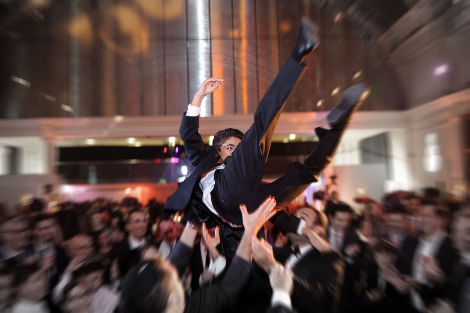 Blurred motion shot of dancers performing at an elegant indoor venue with dramatic lighting and formal attire.
