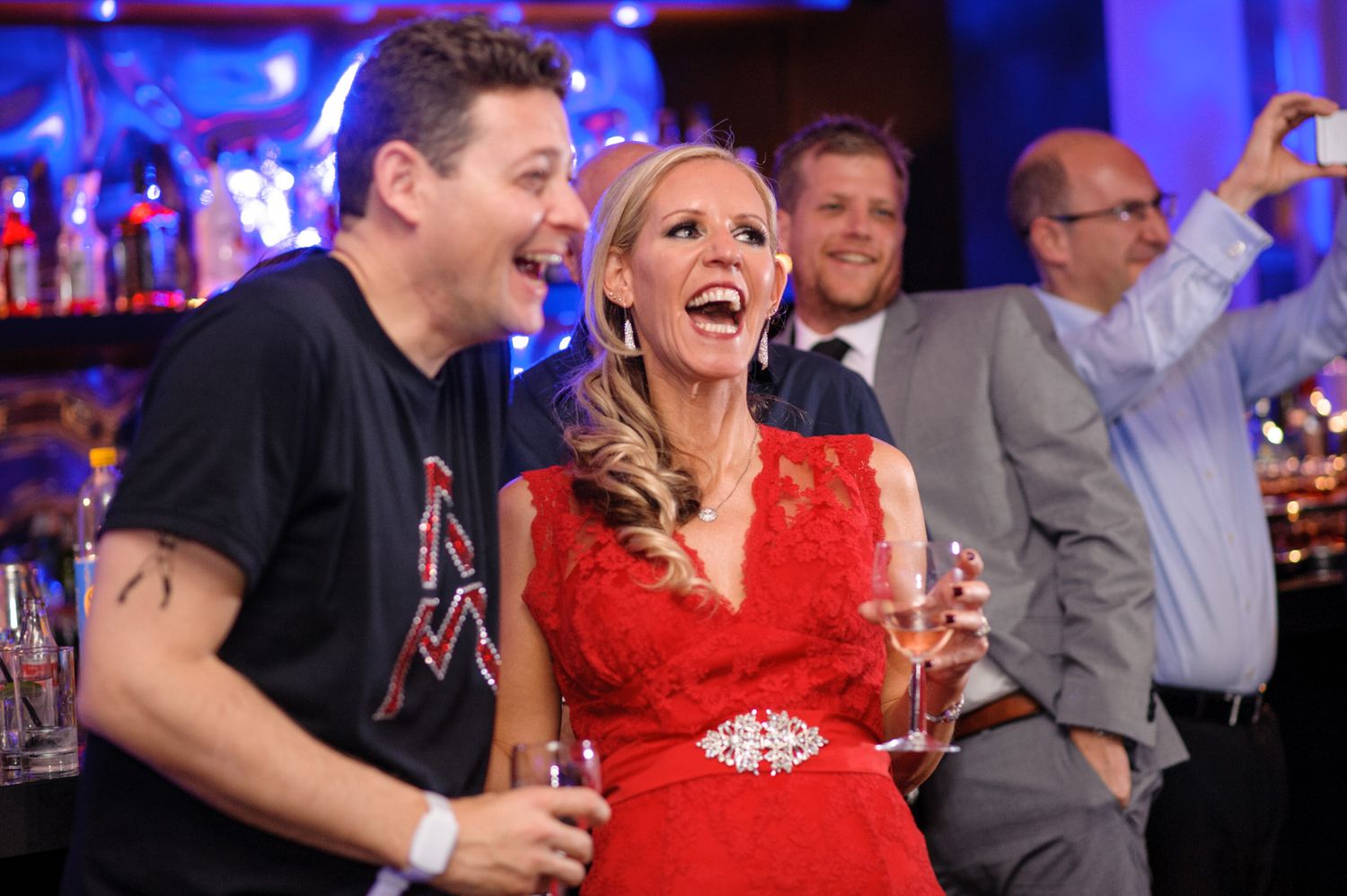 Partygoers laughing and having fun at an event with bright lighting and festive atmosphere.