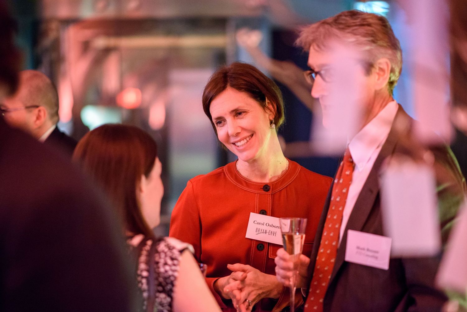 Guests mingle and socialize at an elegant evening event with colorful lighting.