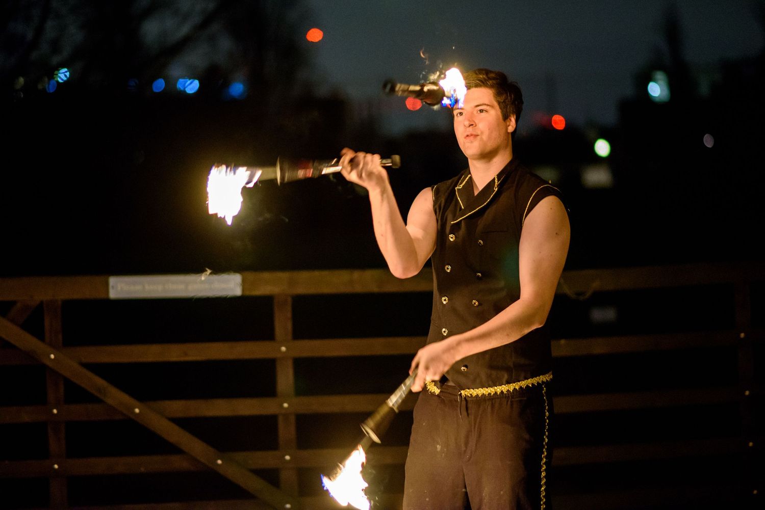 Fire performer spinning flames against dark night sky during outdoor entertainment show.