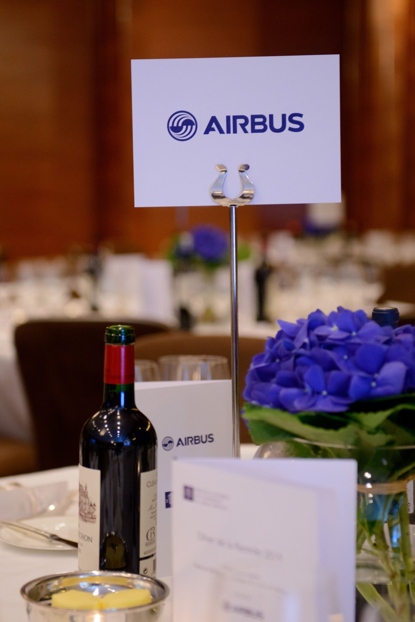 Corporate dining table setup with Airbus branding and blue floral centerpieces.