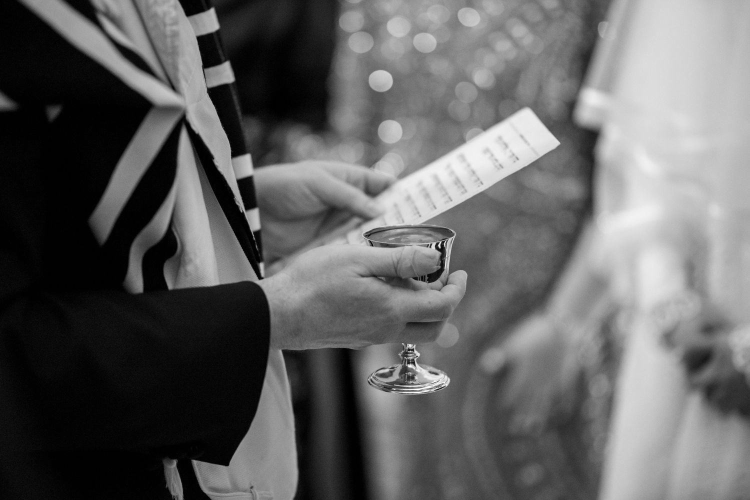 Wedding ceremony details showing hands exchanging rings, signing documents, and holding champagne glasses in black and white.