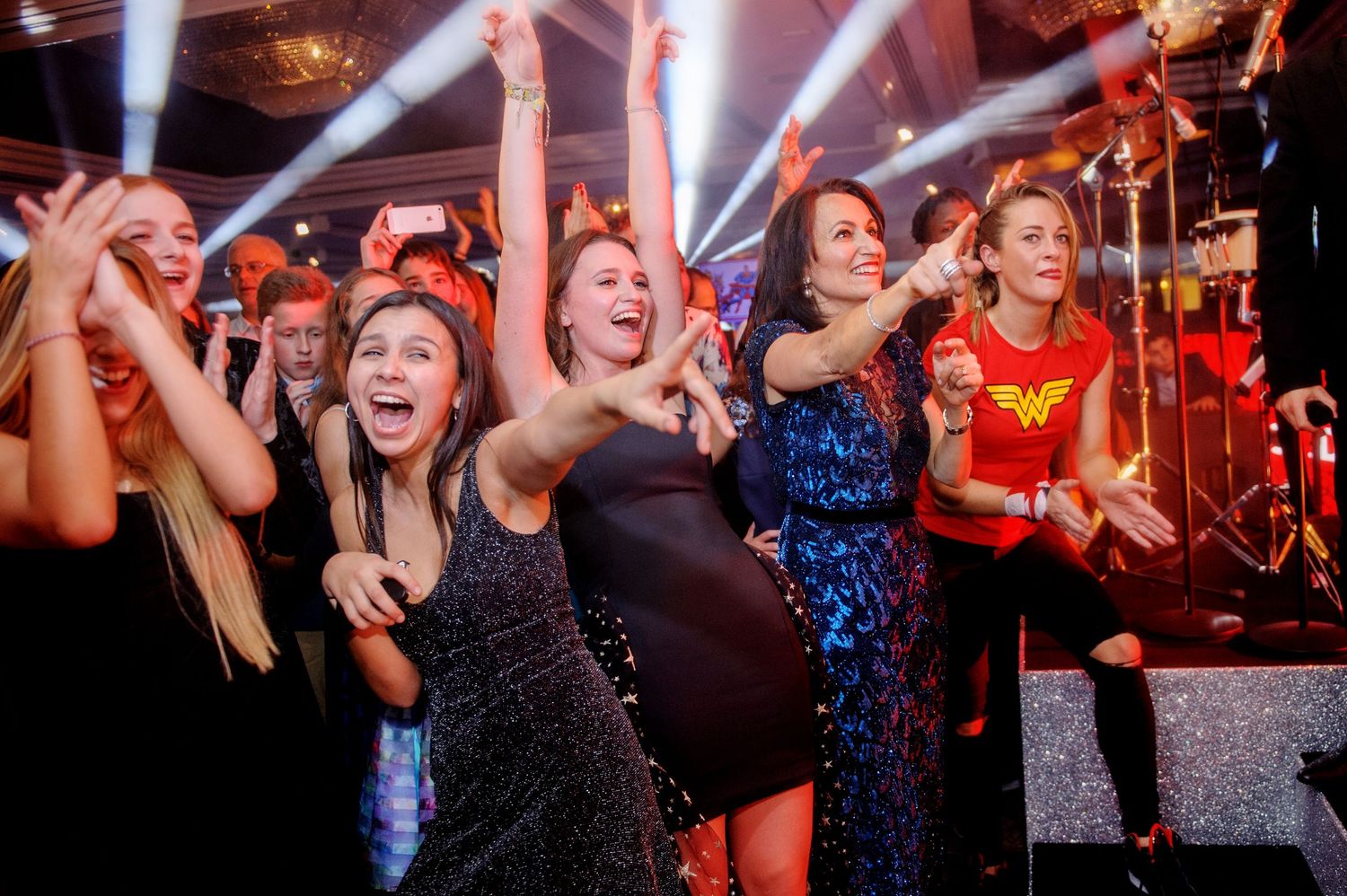 A group of people dancing and celebrating at a nightclub with bright lights and energetic atmosphere.