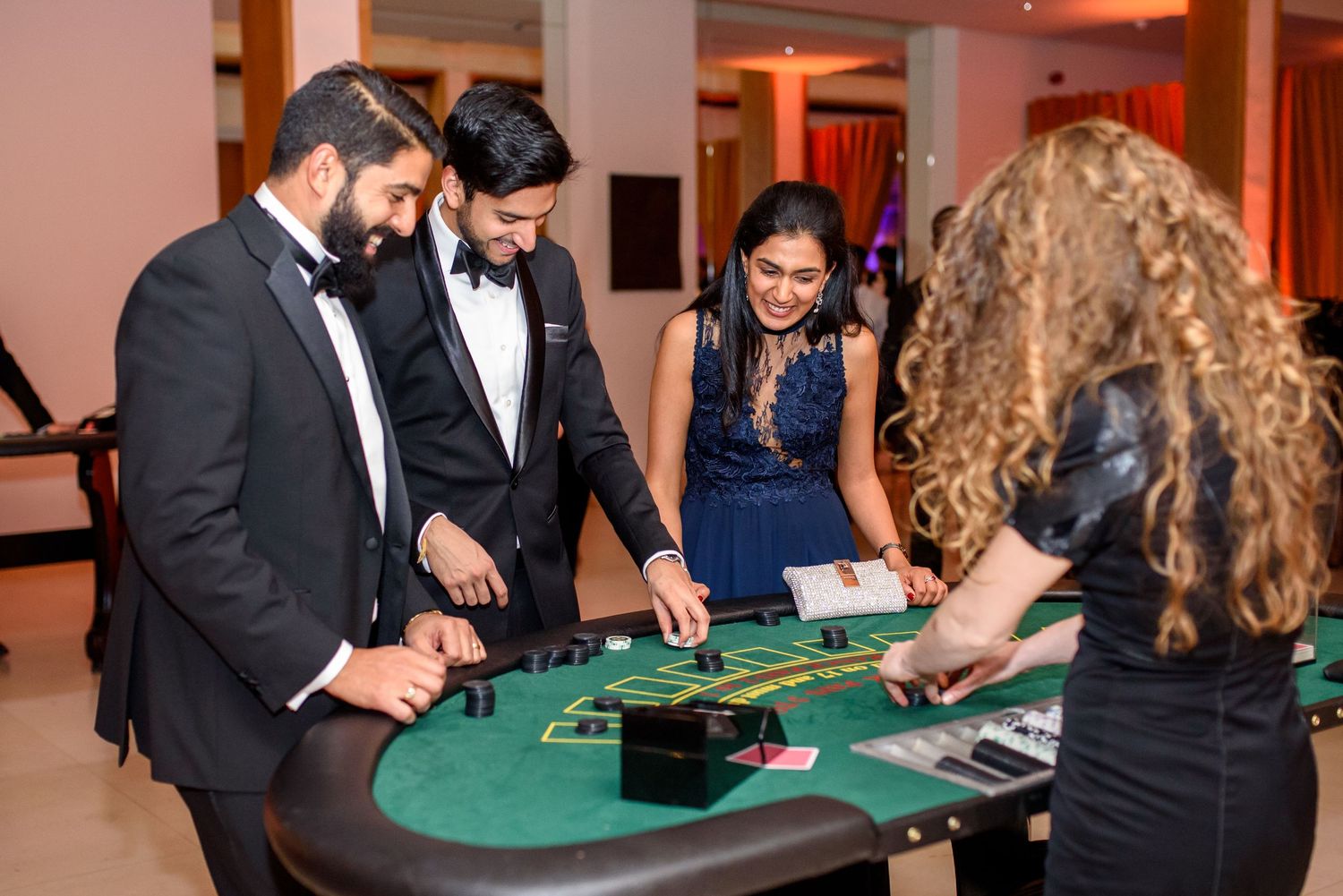 Casino gaming tables with guests playing cards at a formal event.