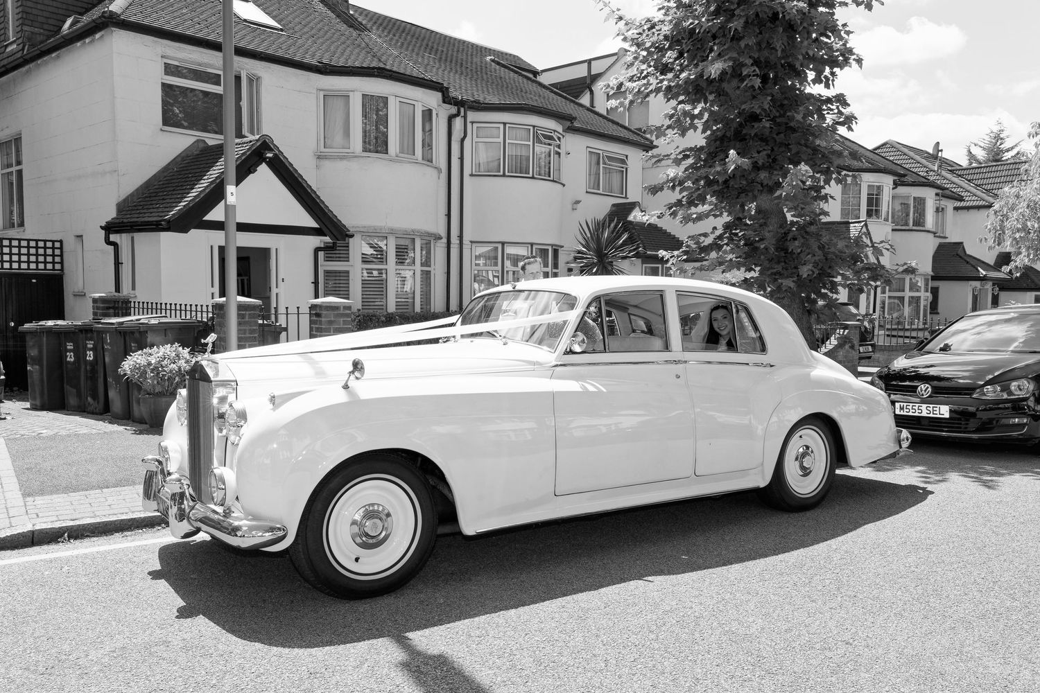 Classic white vintage Rolls Royce cars parked on a residential street showing their elegant profiles and designs.