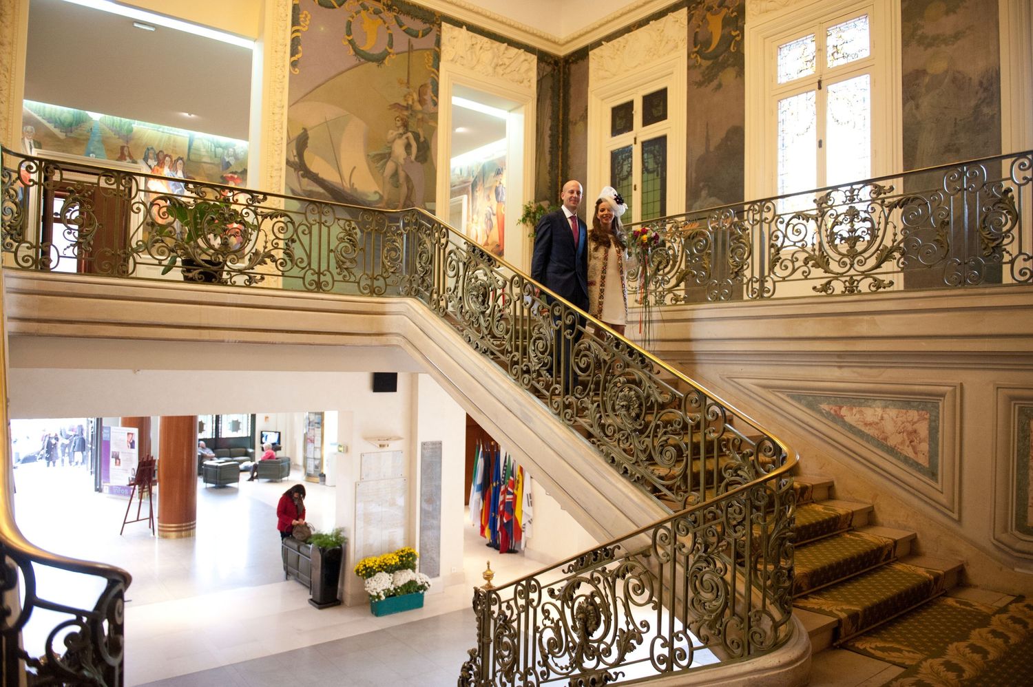 Elegant curved staircase with ornate wrought iron railings and marble steps in a luxurious historic building interior.