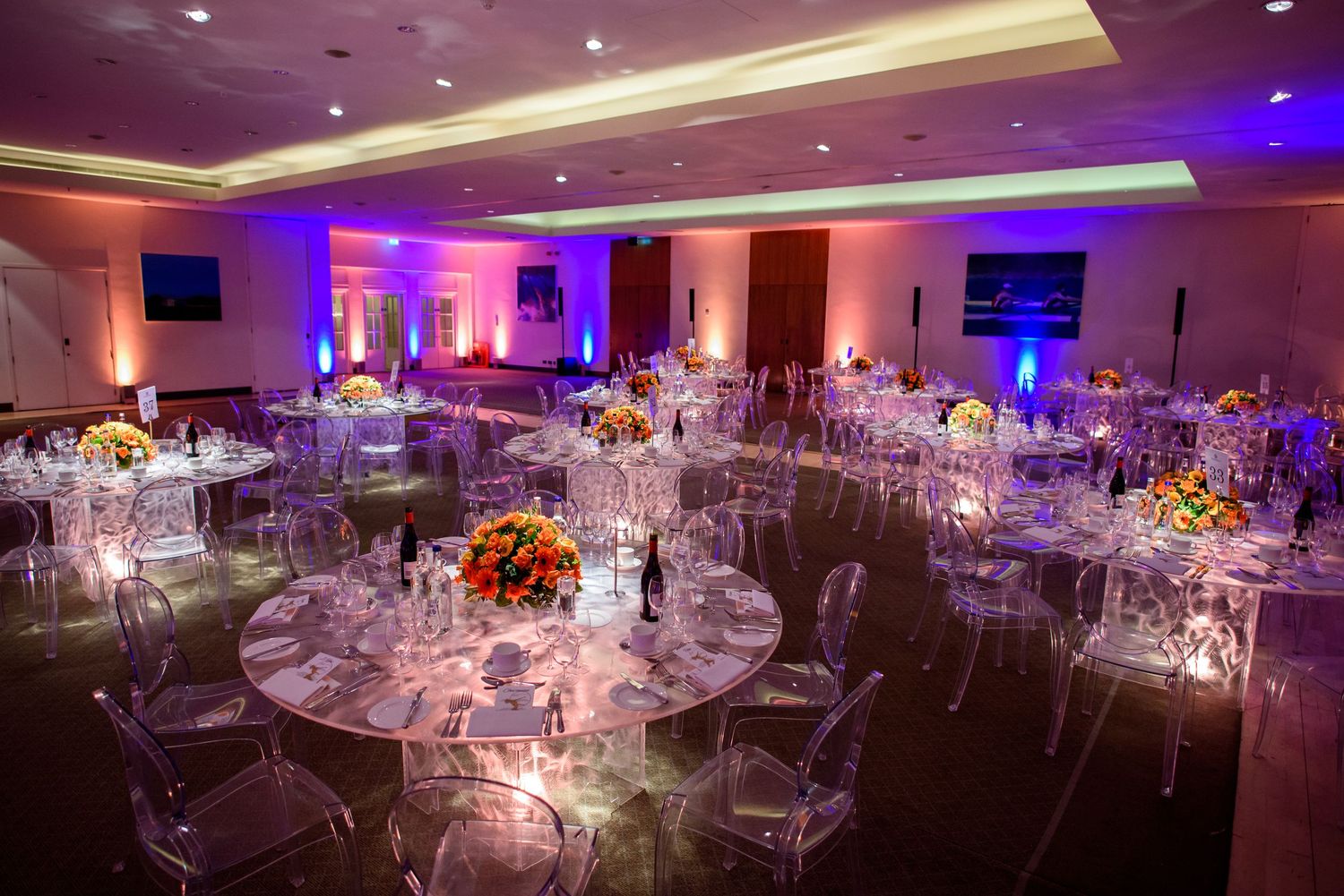 Elegant banquet hall decorated with mood lighting and round tables set for a formal dinner event.