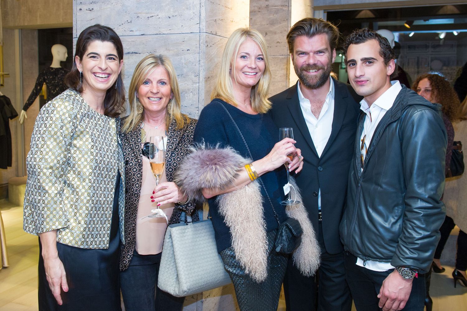 Well-dressed guests mingle and socialize at an elegant indoor event.