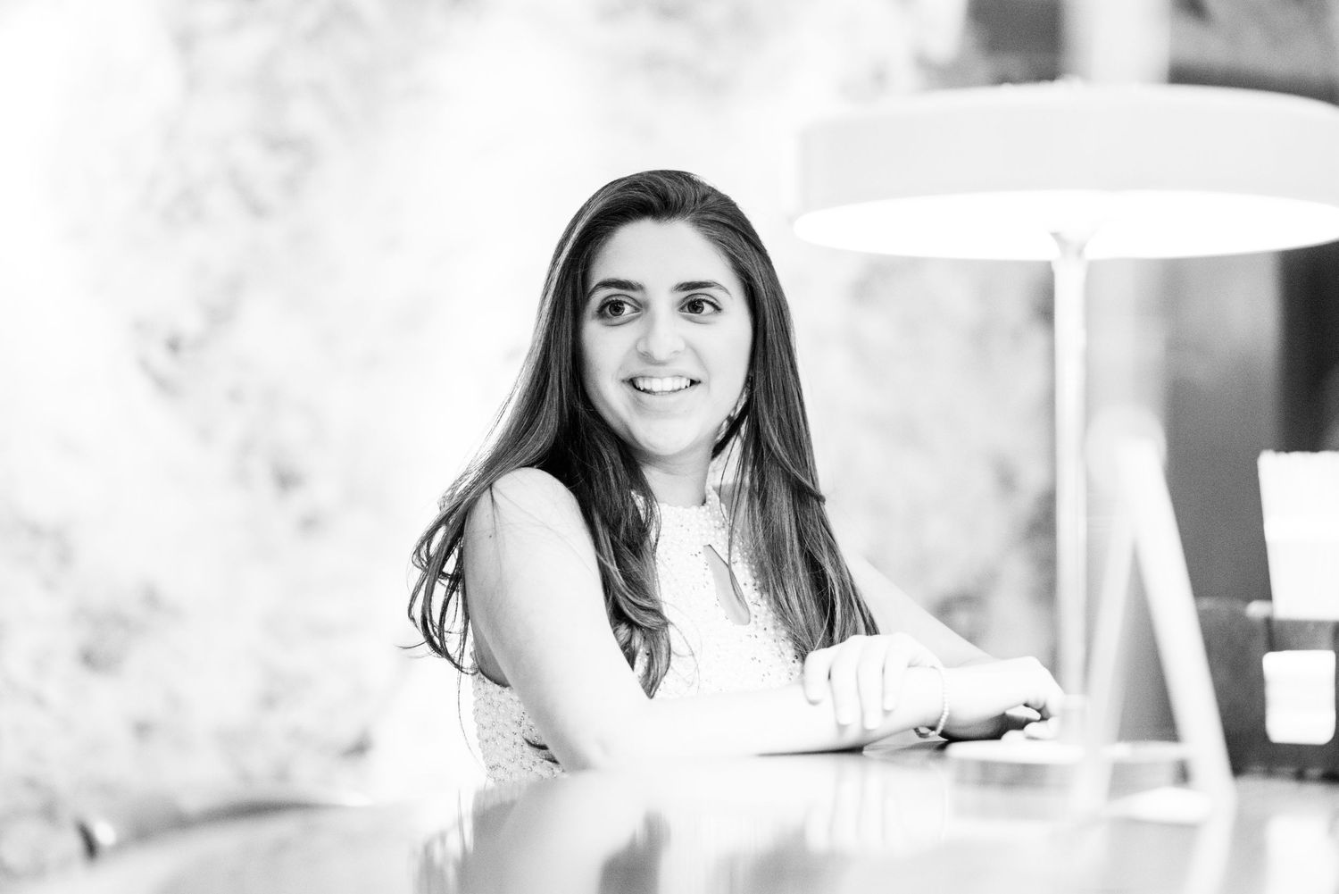 A series of black and white headshots showing a person smiling in different poses against a light background.