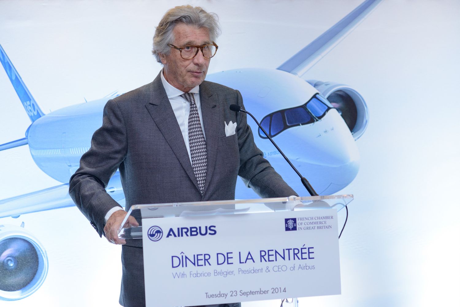 Corporate presentation featuring Airbus branding on stage with blue lighting.