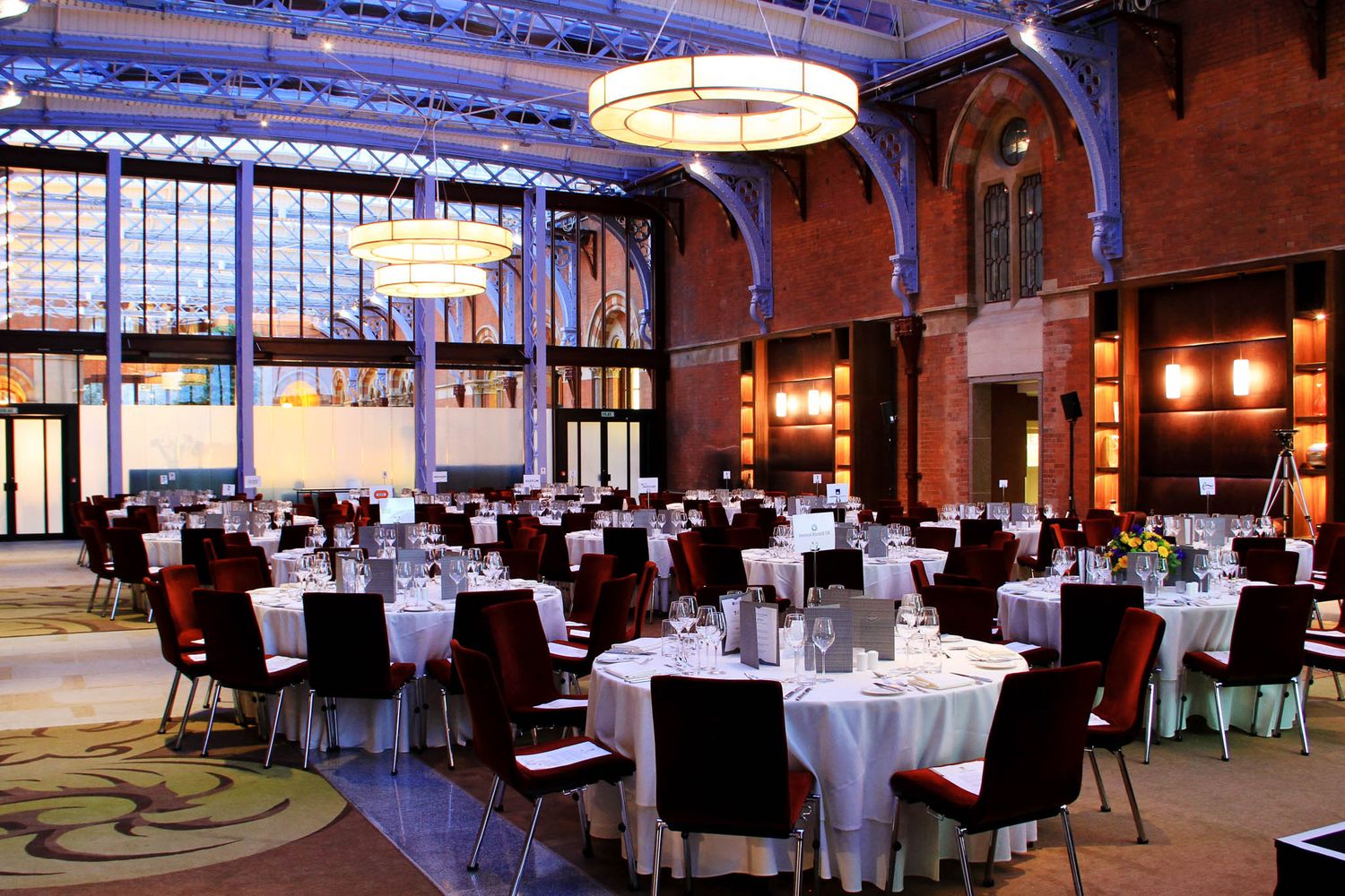 Grand ballroom with white tablecloths and formal dining setup in historic venue.