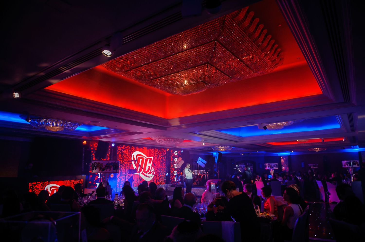 Nightclub interior with red and blue lighting illuminating an ornate ceiling and dance floor area.