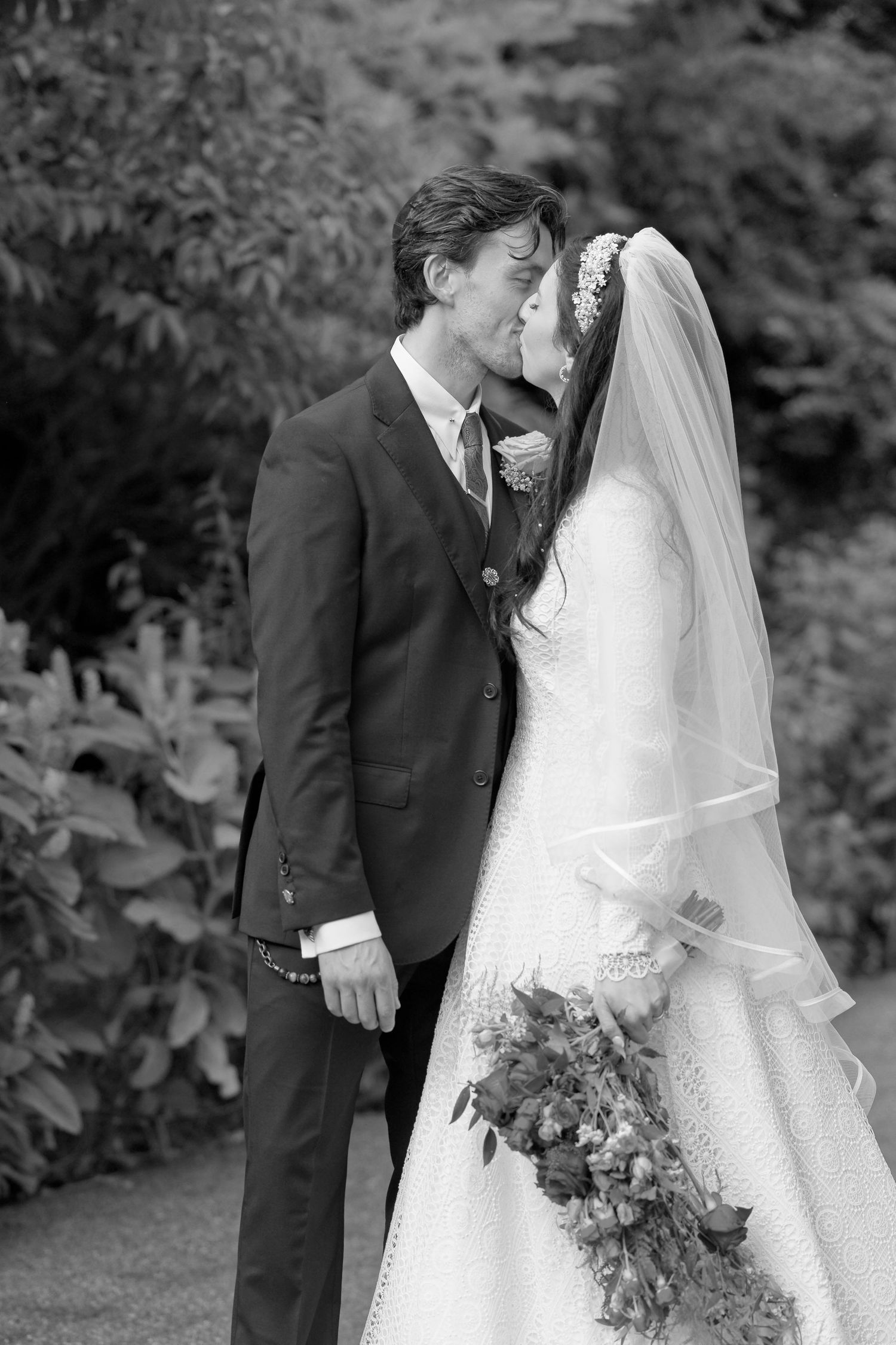 A romantic black and white wedding photo series showing intimate moments between a couple in formal attire outdoors.