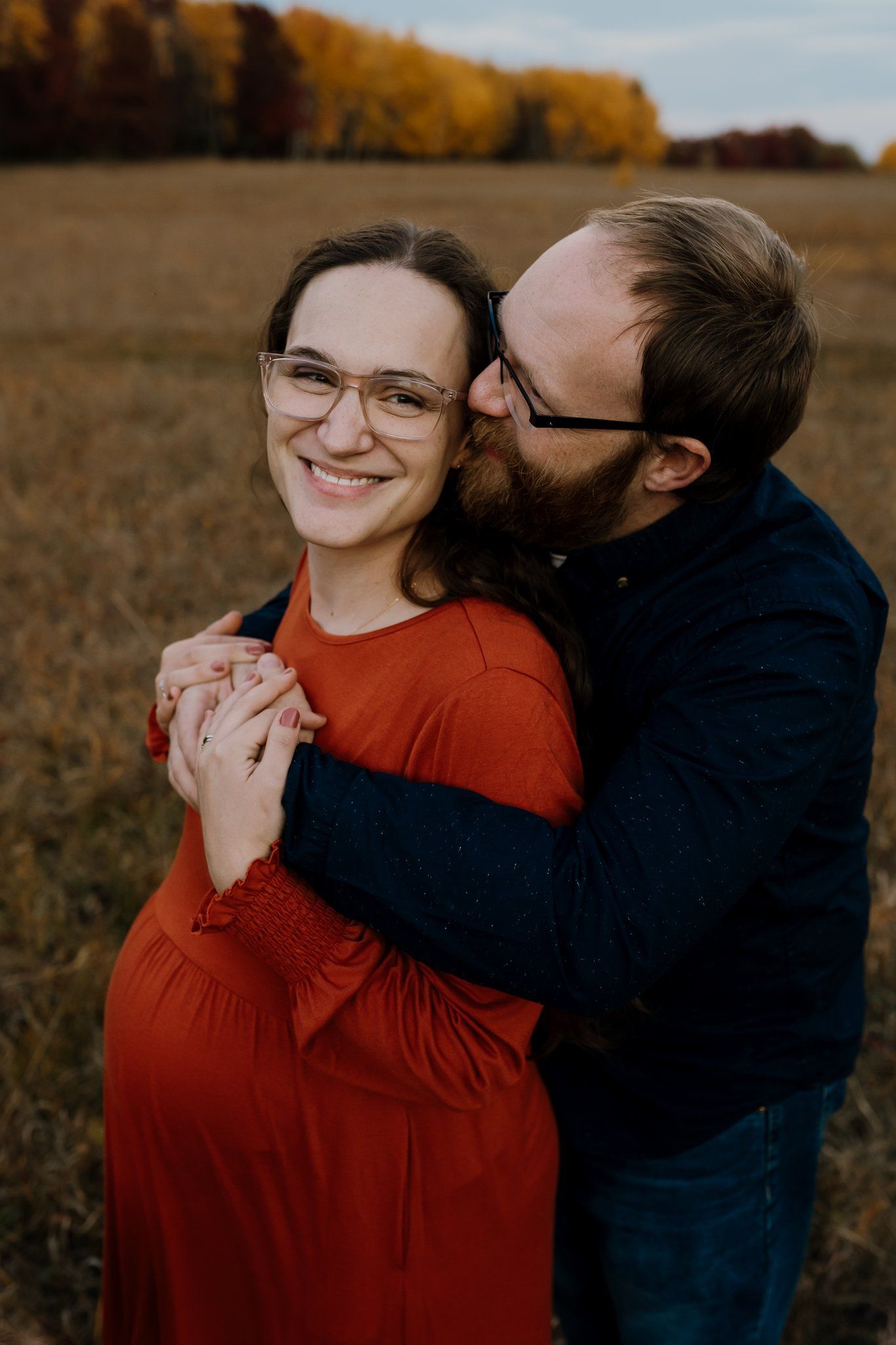 Dad hugs mom and kisses her head as she smiles
