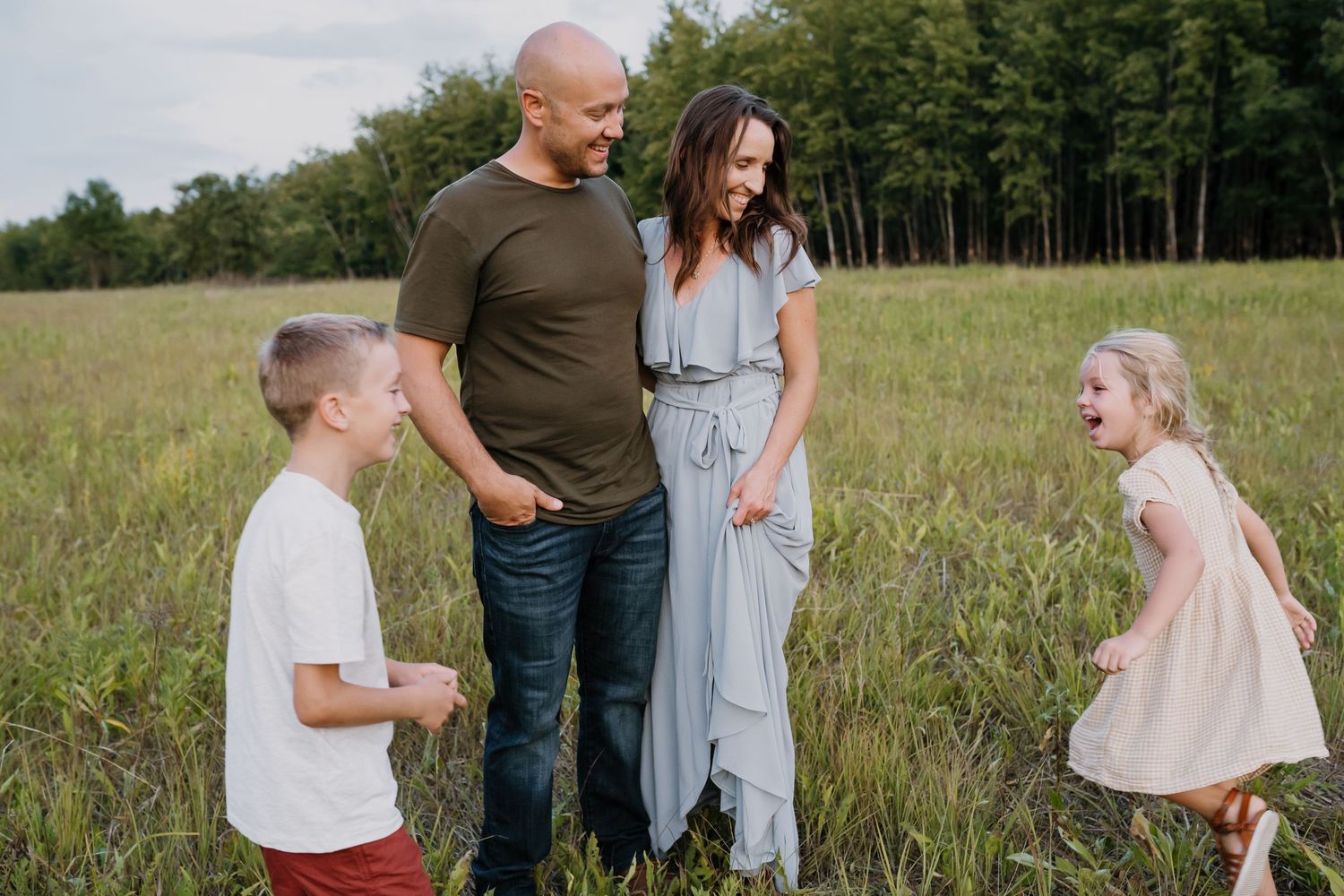 children laughing and running around parents in a field